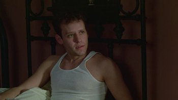 Movie still from “Sophie's Choice” (1982), directed by Alan J. Pakula – A man in a white tank top sitting on a bed; Close Up shot, Low angle