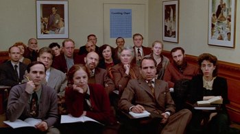 Movie still from “Sophie's Choice” (1982), directed by Alan J. Pakula – A group of people sitting in front of a poster; Wide shot, High angle