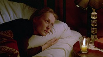 Movie still from “Sophie's Choice” (1982), directed by Alan J. Pakula – A woman laying in a bed with a book in front of her face; Close Up shot, High angle