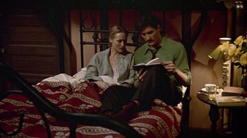 Movie still from “Sophie's Choice” (1982), directed by Alan J. Pakula – A man and a woman sitting on top of a bed reading; Medium shot, High angle