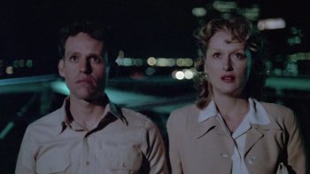 Movie still from “Sophie's Choice” (1982), directed by Alan J. Pakula – A man and a woman standing next to each other in front of lights; Close Up shot, Low angle