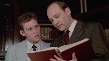 Movie still from “Sophie's Choice” (1982), directed by Alan J. Pakula – Two men in business suits looking at a book; Close Up shot, Low angle