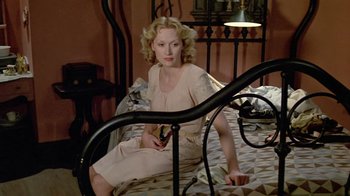 Movie still from “Sophie's Choice” (1982), directed by Alan J. Pakula – A woman sitting on top of a bed holding a cell phone; Wide shot, High angle