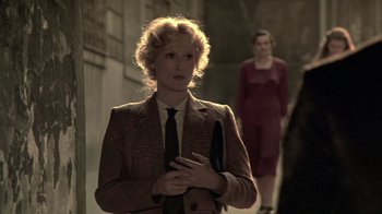 Movie still from “Sophie's Choice” (1982), directed by Alan J. Pakula – A woman standing next to another woman in a suit; Medium shot, Over the shoulder angle