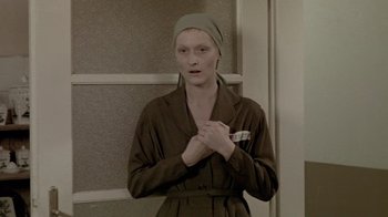 Movie still from “Sophie's Choice” (1982), directed by Alan J. Pakula – A woman in a brown robe and a green head scarf; Close Up shot, Over the shoulder angle