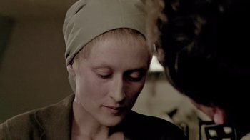 Movie still from “Sophie's Choice” (1982), directed by Alan J. Pakula – A woman wearing a head covering looking down at her face; Close Up shot, Over the shoulder angle