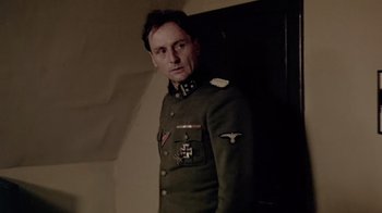 Movie still from “Sophie's Choice” (1982), directed by Alan J. Pakula – A man in a military uniform standing in front of a wall; Medium shot, Over the shoulder angle