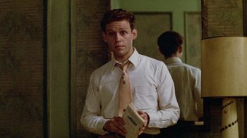 Movie still from “Sophie's Choice” (1982), directed by Alan J. Pakula – A man wearing a tie and holding a book; Medium shot, Low angle