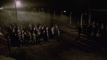 Movie still from “Sophie's Choice” (1982), directed by Alan J. Pakula – A group of people standing next to each other on train tracks at night; Extreme Wide shot, High angle