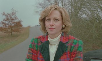 Movie still from “Spencer” (2021), directed by Pablo Larraín – A woman wearing a colorful jacket standing next to a road; Close Up shot, Low angle