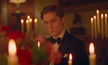 Movie still from “Spencer” (2021), directed by Pablo Larraín – A man in a tuxedo standing in front of candles; Close Up shot, Over the shoulder angle