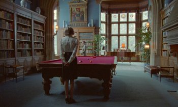 Movie still from “Spencer” (2021), directed by Pablo Larraín – A woman standing in front of a pool table in a room; Wide shot, Over the shoulder angle