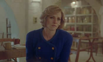 Movie still from “Spencer” (2021), directed by Pablo Larraín – A woman sitting in a chair in front of a table; Close Up shot, Over the shoulder angle