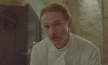 Movie still from “Spencer” (2021), directed by Pablo Larraín – A man in a chef's outfit looking at the camera; Close Up shot, Low angle
