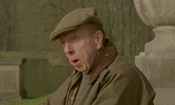 Movie still from “Spencer” (2021), directed by Pablo Larraín – An older man wearing a hat and a jacket; Close Up shot, Over the shoulder angle