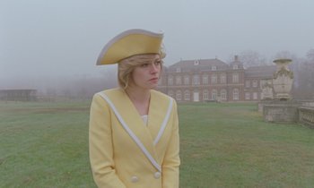 Movie still from “Spencer” (2021), directed by Pablo Larraín – A woman wearing a yellow suit and a hat; Medium shot, Low angle