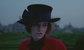 Movie still from “Spencer” (2021), directed by Pablo Larraín – A woman wearing a black hat and a red jacket; Close Up shot, Low angle