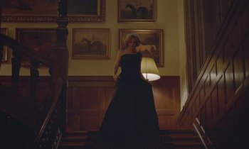 Movie still from “Spencer” (2021), directed by Pablo Larraín – A woman in a black dress standing on a staircase; Wide shot, Low angle
