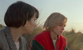 Movie still from “Spencer” (2021), directed by Pablo Larraín – Two women sitting next to each other on a field; Close Up shot, Over the shoulder angle
