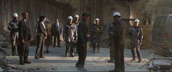 Movie still from “Spider-Man: Homecoming” (2017), directed by Jon Watts – A group of men standing next to each other in front of a wall; Wide shot, Over the shoulder angle