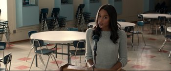 Movie still from “Spider-Man: Homecoming” (2017), directed by Jon Watts – A woman standing at a podium speaking into a microphone; Medium shot, Over the shoulder angle