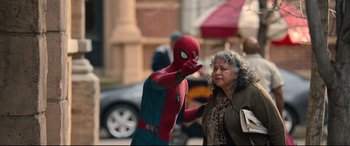 Movie still from “Spider-Man: Homecoming” (2017), directed by Jon Watts – A man dressed as spider - man and an older woman on the street; Medium shot, Over the shoulder angle