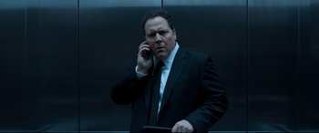 Movie still from “Spider-Man: Homecoming” (2017), directed by Jon Watts – A man in a suit and tie talking on a cell phone; Close Up shot, Low angle