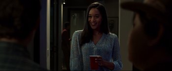 Movie still from “Spider-Man: Homecoming” (2017), directed by Jon Watts – A woman holding a cup and smiling for the camera; Medium shot, Over the shoulder angle