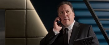 Movie still from “Spider-Man: Homecoming” (2017), directed by Jon Watts – A man in a suit and tie talking on a cell phone; Close Up shot, Low angle
