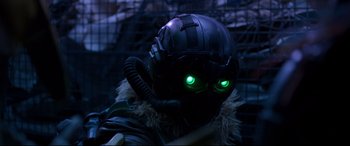 Movie still from “Spider-Man: Homecoming” (2017), directed by Jon Watts – A person wearing a helmet with green eyes; Close Up shot, Over the shoulder angle