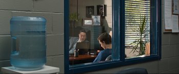 Movie still from “Spider-Man: Homecoming” (2017), directed by Jon Watts – A man sitting in front of an open laptop computer in front of another man; Wide shot, Over the shoulder angle