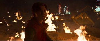 Movie still from “Spider-Man: Homecoming” (2017), directed by Jon Watts – A man standing in front of a fire at night; Medium shot, Over the shoulder angle