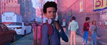 Movie still from “Spider-Man: Into the Spider-Verse” (2018), directed by Peter Ramsey – A young man holding a pink backpack while standing on a sidewalk; Medium shot, Over the shoulder angle