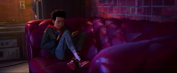 Movie still from “Spider-Man: Into the Spider-Verse” (2018), directed by Peter Ramsey – A person sitting on a couch in a living room; Medium shot, High angle