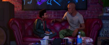 Movie still from “Spider-Man: Into the Spider-Verse” (2018), directed by Peter Ramsey – Two people sitting on a red couch in a room; Wide shot, Over the shoulder angle
