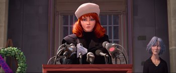Movie still from “Spider-Man: Into the Spider-Verse” (2018), directed by Peter Ramsey – A red haired woman wearing a white hat is sitting at a press conference with microphones in front of her; Medium shot, Low angle