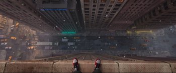 Movie still from “Spider-Man: Into the Spider-Verse” (2018), directed by Peter Ramsey – A person standing on a ledge in front of a city; Extreme Wide shot, Overhead angle