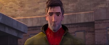 Movie still from “Spider-Man: Into the Spider-Verse” (2018), directed by Peter Ramsey – A man with a spider - man shirt on is looking at the camera; Close Up shot, Over the shoulder angle