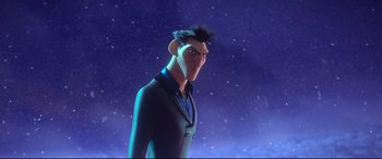 Movie still from “Spies in Disguise” (2019), directed by Troy Quane – A man in a black suit standing in front of a night sky; Medium shot, Low angle