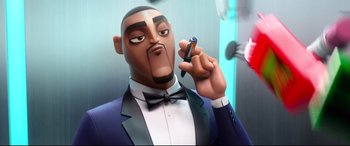 Movie still from “Spies in Disguise” (2019), directed by Troy Quane – A man in a suit and bow tie holding a cell phone; Close Up shot, Low angle