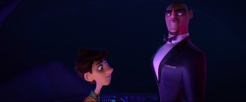 Movie still from “Spies in Disguise” (2019), directed by Troy Quane – A man standing next to a woman in a purple suit; Medium shot, Over the shoulder angle