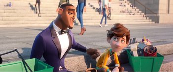 Movie still from “Spies in Disguise” (2019), directed by Troy Quane – A man and a boy sitting on the ground in front of a crowd; Medium shot, Over the shoulder angle