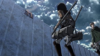 Movie still from “Attack on Titan” (2013), directed by Masashi Koizuka – An anime character is standing in front of a stone wall; Wide shot, Low angle