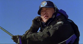Movie still from “Audition” (1999), directed by Takashi Miike – A man wearing a hat and gloves is talking on a cell phone; Close Up shot, Low angle