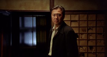 A man in a suit and tie standing in front of a window