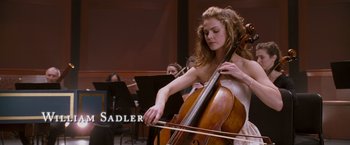 Movie still from “August Rush” (2007), directed by Kirsten Sheridan – A woman is playing the cello in front of other people; Medium shot, Low angle