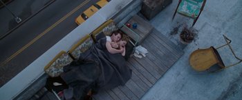 Movie still from “August Rush” (2007), directed by Kirsten Sheridan – Two people sleeping on a porch next to a yellow bus; Wide shot, Overhead angle