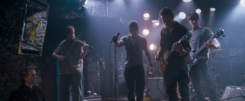 Movie still from “August Rush” (2007), directed by Kirsten Sheridan – A group of people standing in a room with instruments; Wide shot, Low angle