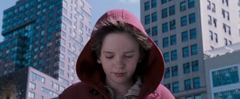 Movie still from “August Rush” (2007), directed by Kirsten Sheridan – A young boy wearing a hooded jacket in front of some buildings; Close Up shot, Low angle