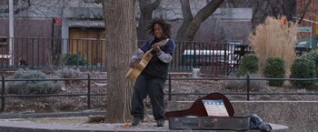 Movie still from “August Rush” (2007), directed by Kirsten Sheridan – A man playing a guitar in a park setting; Wide shot, Over the shoulder angle